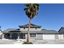 Charming two-story home with a palm tree, gray stucco, gray roof, and well maintained front yard at 1300 Oak Tree Ln, Las Vegas, NV 89108