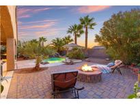 Inviting backyard with a sparkling pool, firepit, beautiful landscaping, and a serene lounging area at 1065 Otto Ridge Ct, Henderson, NV 89052