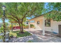 Charming backyard patio with mature tree, swing, and walkway with elegant lamp post at 1720 Weeping Willow Ln, Las Vegas, NV 89104