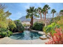 Beautiful pool featuring a waterfall, lush landscaping, and palm trees providing a tranquil backyard oasis at 194 Carlsbad Caverns St, Henderson, NV 89012