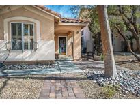 Charming single-story home featuring desert landscaping, a brick walkway, and a covered front porch at 283 New River Cir, Henderson, NV 89052