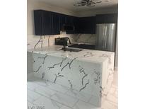 Modern kitchen featuring dark blue cabinets and a white marble countertop with black veins at 2970 Juniper Hills Blvd # 102, Las Vegas, NV 89142