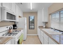 Bright kitchen features white cabinets, granite countertops, and modern appliances at 4861 S Torrey Pines Dr # 201, Las Vegas, NV 89103