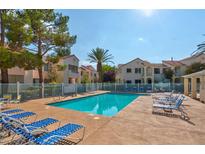 Community pool with lounge chairs surrounded by lush landscaping and lovely villa-style buildings on a bright sunny day at 4861 S Torrey Pines Dr # 201, Las Vegas, NV 89103