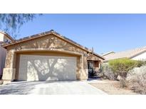 Tan single story home featuring a two car garage and desert landscaping at 6533 Adonis Heights Ave, North Las Vegas, NV 89086