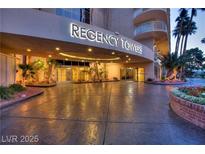 Regency Towers building entrance featuring palm trees, covered entrance, and ample parking space at 3111 Bel Air Dr # 20D, Las Vegas, NV 89109