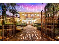 Elegant estate home with a gated entrance, lush landscaping, and stone pathway at 9940 Orient Express Ct, Las Vegas, NV 89145