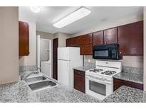 Functional kitchen featuring granite countertops, white appliances, and wood cabinetry at 2200 S Fort Apache Rd # 2175, Las Vegas, NV 89117