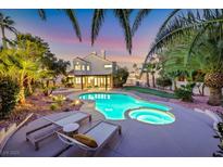 A backyard with a pool, hot tub, landscaping, and lounge chairs, perfect for relaxation and entertainment at 9 Cozy Glen Cir, Henderson, NV 89074