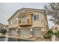 Charming townhome featuring three garage doors, a small balcony, and desert landscaping at 10147 Aspen Rose St # 101, Las Vegas, NV 89183