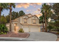 Two-story home featuring a three-car garage, desert landscaping, and mature palm trees at 399 Placer Creek Ln, Henderson, NV 89014