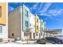 View of modern colorful townhomes with covered parking and well-maintained landscaping on a sunny day at 9160 Coral Cascade Ave, Las Vegas, NV 89141