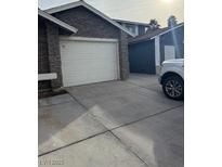 Exterior of home with a large white garage door with stacked stone accents and driveway at , Las Vegas, NV 89110