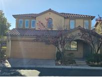 Two story home featuring a large front-facing two car garage, desert landscaping, and a tile roof at 6055 Devers Ct, Las Vegas, NV 89118