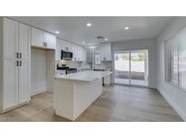 Bright kitchen features white cabinets, modern appliances, quartz countertops, and a breakfast bar island at 8712 Majestic Pine Ave, Las Vegas, NV 89143