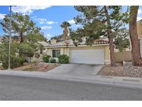 Charming single-story home featuring a well-maintained front yard, a two-car garage, and mature trees at 7713 Shore Haven Dr, Las Vegas, NV 89128