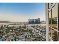 Expansive view features a resort pool, palm trees, the Las Vegas Strip, and a clear blue sky at 145 E Harmon Ave # 1202, Las Vegas, NV 89109