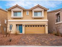 Two-story home featuring tan siding, a tan two-car garage, and a landscaped front yard at 7748 Westwind Rd, Las Vegas, NV 89139