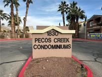 Pecos Creek Condominiums' sign surrounded by lush palm trees under a partly cloudy sky at 1830 N Pecos Rd # 230, Las Vegas, NV 89115
