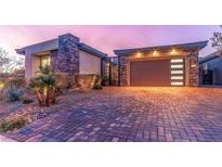 Charming single-story home featuring stone accents, desert landscaping, and a brick driveway at dusk at 106 Reflection Bay Dr, Henderson, NV 89011
