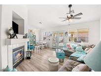 Bright living room with a cozy fireplace, ceiling fan, and charming decor for a warm, inviting atmosphere at 266 Corvallis Ct, Henderson, NV 89074
