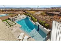 Inviting backyard pool with turf, desert landscaping, sun-bathing chairs, steps, and views of the surrounding landscape at 11943 Rockview Point St, Las Vegas, NV 89138