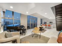 Bright, modern living room features a grand piano, sleek furnishings, and expansive windows with stunning city views at 353 E Bonneville Ave # 1407, Las Vegas, NV 89101