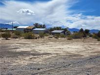 Exterior view of a residence, showing desert landscaping under a partly cloudy sky and distant mountain views at 81 W Mesquite Ave, Pahrump, NV 89060