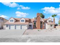 Charming single Gathering home showcasing manicured front yard, three-car garage and beautiful brick chimney at 2160 Pueblo Cir, Las Vegas, NV 89169