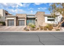 Striking modern home featuring a three-car garage, landscaped front yard, and stone facade at 32 Hunting Horn Dr, Las Vegas, NV 89135