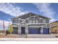 Charming two-story home boasts a gray exterior, blue garage doors, and a well-manicured front yard at 7812 Alola Springs Ln # Lot 1, North Las Vegas, NV 89084