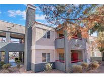 Exterior view of a multi-story condo featuring a chimney, balconies, and desert landscaping at 8600 W Charleston Blvd # 2108, Las Vegas, NV 89117