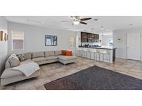 Open concept living room featuring a large sectional sofa, ceiling fan and view of the kitchen at 10525 Gibbous Moon Dr, Las Vegas, NV 89129