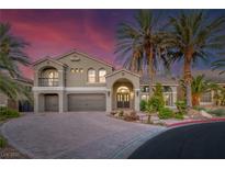 Stunning stucco home boasts an arched entryway, three-car garage, desert landscaping, and mature palm trees at 11158 Antonine Wall Ct, Las Vegas, NV 89141