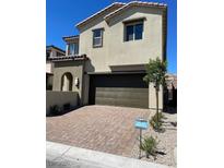 Two-story home with brick driveway, two-car garage, and desert landscaping under a bright blue sky at 145 Medianoche St, Las Vegas, NV 89138