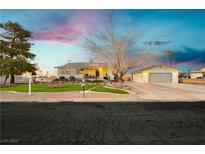 Charming single-story home with mature trees, green lawn, a garage, and long driveway at dusk at 200 E Desert Rose Dr, Henderson, NV 89015
