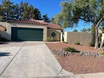 Charming home featuring a green garage door, a red tile roof and desert landscaping at 2711 Seabridge Dr, Las Vegas, NV 89121