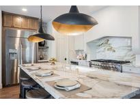 Modern kitchen features a large island with marble countertops, pendant lighting, and stainless steel appliances at 501 Proud Eagle Ln, Las Vegas, NV 89144