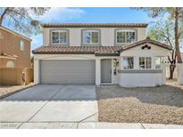 Two-story home with gray garage door, desert landscaping, and light-colored exterior paint at 8979 Green Jade Dr, Las Vegas, NV 89129