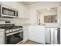 Bright kitchen featuring stainless steel appliances, white cabinets, and view into other living space at 9001 Marble Dr, Las Vegas, NV 89134