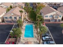 Aerial view of a community pool with palm trees, lounge chairs, and nearby residential buildings at 1292 Large Cap Dr # 3, Henderson, NV 89074