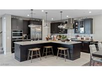 Modern kitchen with dark cabinetry, stainless steel appliances, large center island, and pendant lighting at 2518 Veronella St, Henderson, NV 89044