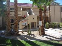 View of a two-story condo building with desert landscaping, including palm trees and cacti at 3781 Desert Marina Dr # 101, Laughlin, NV 89029