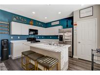 Well-lit kitchen with white cabinetry, stainless steel appliances, and a center island with barstool seating at 3898 Blake Canyon Dr, North Las Vegas, NV 89032