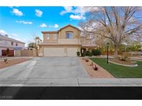 Two-story tan home featuring a three-car garage and a well-maintained front yard at 4933 Gate Fall Ct, Las Vegas, NV 89149