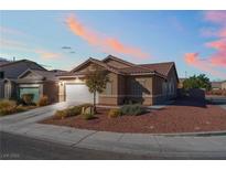 Charming single-story home with a two-car garage, desert landscaping, and a tile roof at sunset at 6061 Leaping Foal St, North Las Vegas, NV 89081