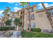 Beige two-story condo with palm trees and green landscaping under a beautiful blue, partly cloudy sky at 7115 S Durango Dr # 313, Las Vegas, NV 89113