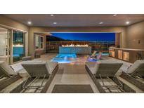 Inviting outdoor patio with a pool, fireplace, outdoor kitchen, and lounge chairs for relaxation at 10096 Amethyst Hills St, Las Vegas, NV 89148