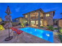 Stunning backyard pool with a covered patio and lush landscaping at dusk at 12356 Grey Dunes Ave, Las Vegas, NV 89138