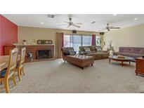 Bright living room featuring a fireplace, multiple sofas, ceiling fans and sliding glass doors to the backyard at 5109 Sugarfoot Ave, Las Vegas, NV 89107